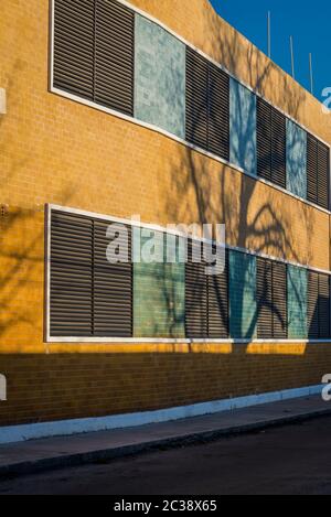 Modernes Bürogebäude mit geschlossenen Fensterläden und Baumschatten, Merida, Mexiko Stockfoto