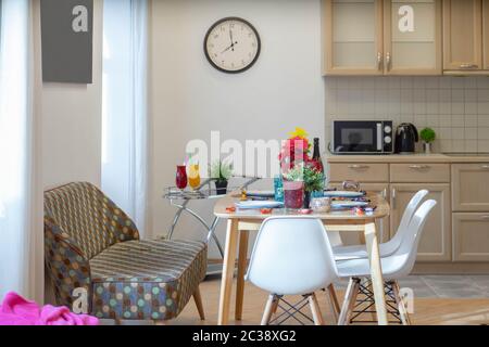 Moderne Einrichtung der Küche in Luxus-Studio-Wohnung. Nahaufnahme des gemütlichen Sofas, des gedeckten Tisches und der Stühle. Küchenset. Stockfoto