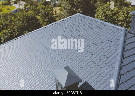 Modernes Dach aus Metall. Grau-blaue Metalldachziegel auf dem Dach des Hauses. Wellblech Dach und Metalldach. Stockfoto