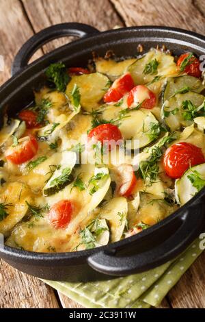 Gebackene Zucchini mit Käse und Tomaten in einer Pfanne auf dem Tisch. Vertikal Stockfoto