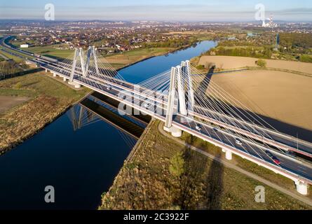 Neue moderne Doppelseilbrücke mit breiten dreispurigen Straßen über der Weichsel in Krakau, Polen, und ihre Reflexion im Wasser bei Sonnenaufgang. Teil von Stockfoto