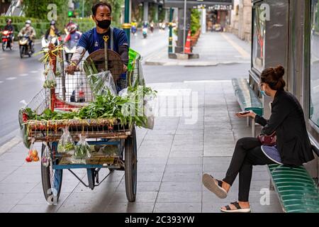 Straßenverkäufer und Passagier an der Bushaltestelle mit Gesichtsmasken während der Covid 19 Pandemie, Bangkok, Thailand Stockfoto