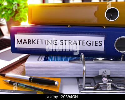 Blue Office-Ordner mit Inschrift Marketing-Strategien auf Office-Desktop mit Bürobedarf und modernen Laptop. Marketing-Strategien Business Conce Stockfoto