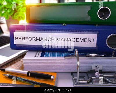 Blauer Office-Ordner mit Aufschrift Performance Management auf Office-Desktop mit Bürobedarf und modernem Laptop. Leistungsmanagement Business C Stockfoto