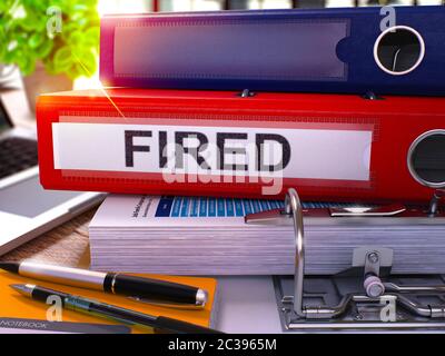 Roter Ringordner mit Beschriftung auf Hintergrund des Arbeitstisch mit Bürobedarf und Laptop gefeuert. Gefeuert - Getönte Abbildung. Gefeuerte Geschäftskonz Stockfoto