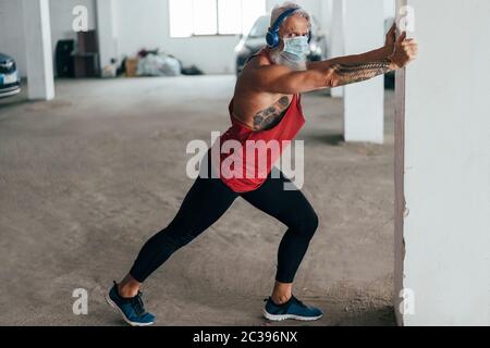 Senior Mann tun Stretching vor dem Training im Pubblic Garage Park, während das Tragen von Gesichtsschutz Maske - Fitness, Sport und gesunde ältere livestyl Stockfoto