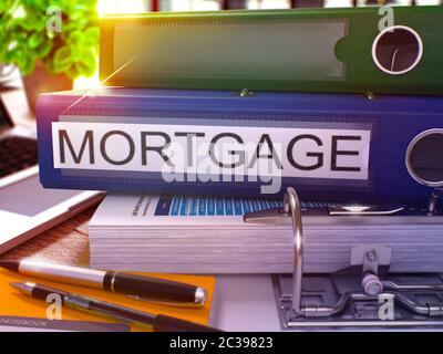 Blue Office Ordner mit Inschrift Hypothek auf Office-Desktop mit Bürobedarf und modernen Laptop. Hypothek Business Konzept auf verschwommenem Hintergrund Stockfoto