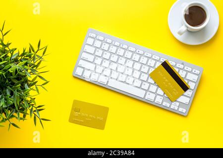 Online-Zahlung einkaufen. Karte auf der Tastatur auf dem gelben Schreibtisch oben nach unten Stockfoto