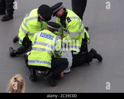 London, Großbritannien 11. April 2010 britische Polizisten verhaften einen Mann vor einem Fußballspiel und zeigen, wie sie sich mit Arm und Hand am Hals zurückhalten, im Gegensatz zu einem Knie, das von Polizisten in den USA verwendet wird Stockfoto