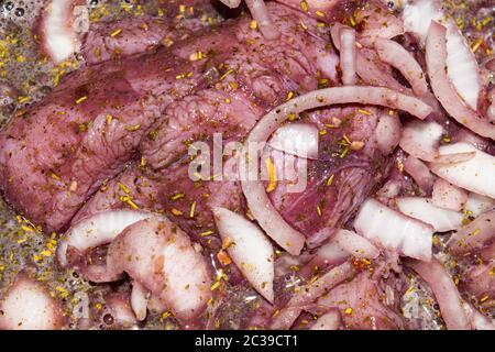Putenfleisch in Stücke geschnitten und in Rotwein mit Zwiebeln und Gewürzen mariniert. Nahaufnahme, Oberflächenstruktur Stockfoto