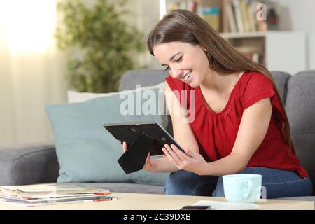 Glückliche Frau erinnern an Bilderrahmen auf einer Couch im Wohnzimmer zu Hause sitzen auf der Suche Stockfoto