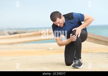 Schmerzhafte runner Beschweren leiden Knie schmerzen nach dem Sport am Strand Stockfoto