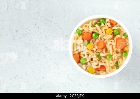 Ramen Becher, Soba-Nudeln in einem Plastikbecher, mit grünen Erbsen, Karottenstücken und Hengsten, Top-Down-Schuss mit Copyspace Stockfoto