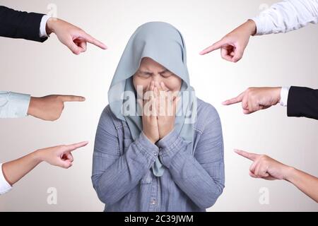 Traurige ängstliche asiatische muslimische Frau, die von verschiedenen Händen beurteilt wird. Konzept der Anklage des schuldigen Mädchen. Weinende Frau Stockfoto