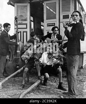 Eine Gruppe von Kindern und Jugendlichen der Sinti und Roma spielt vor einer Karawane Musik. Undatierte Fotografie aus den 1950er Jahren. Stockfoto