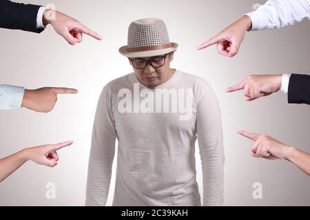 Traurig ängstlich asiatischen Mann beurteilt durch verschiedene Hände. Konzept der Anklage der Schuldigen Person, Schikanierung Konzept Stockfoto