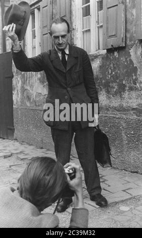 Ein Mann zieht sich zu einem Fotografen auf der Straße. Das Bild stammt aus einem Bericht mit dem Titel 'wie geht es Ihnen Herr Hansen?' ('wie geht es Ihnen, Herr Hansen?') Undatierte Aufnahme. Stockfoto