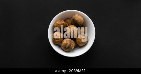 Walnuss in einem kleinen Teller auf einem schwarzen Tisch. Walnüsse ist ein gesundes vegetarisches Protein nahrhafte Lebensmittel. Snacks mit Naturnüssen. Stockfoto