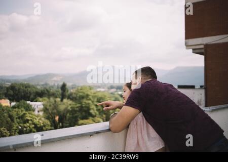 Papa kuschelt seine Tochter, während er sich auf den Zaun lehnt Stockfoto