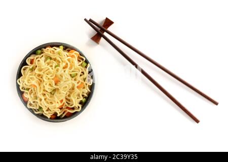Sofort-Nudeln-Schüssel mit Karotte und Hengst, mit Essstäbchen, von oben auf weißem Hintergrund geschossen Stockfoto