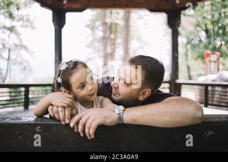 Mann und kleines Mädchen, die sich im Pavillon auf einen Holzzaun stützen Stockfoto