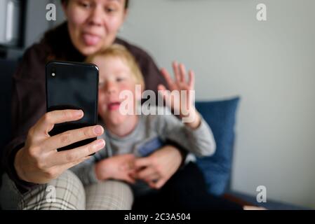 Mutter und Kind, die Videoanruf haben, zusammen lächeln, Sprache zeigen Stockfoto