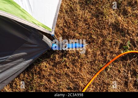 Camping. Eine Zeltstange, die mit einem Zeltpflock am Boden befestigt ist. Stockfoto