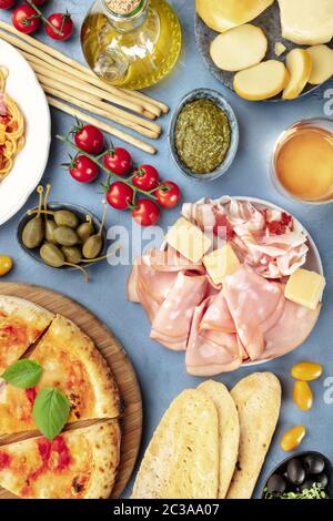 Italienische Küche, Antipasti Overhead mit Pizza. Käse, Schinken, Kapern, Wein, Tomaten, Pesto, Gissini, von oben geschossen Stockfoto