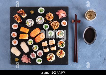 Großes Sushi-Set, von oben mit Sake, Sojasoße und Essstäbchen aufgenommen. Eine Auswahl an verschiedenen Maki, Nigiri und Brötchen Stockfoto
