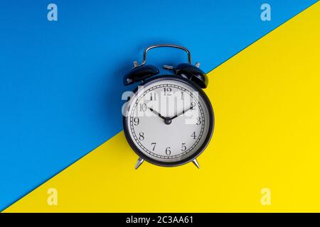 Wecker auf blauem und gelbem Hintergrund. Geschäftskonzept Stockfoto