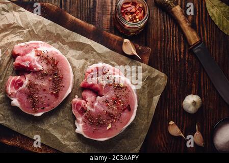 Raw Schweinelende Steaks mit verschiedenen Gewürzen, auf Backpapier Stockfoto