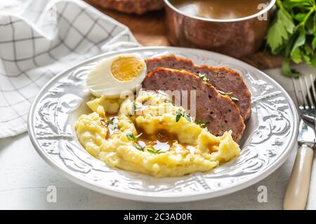 Hausgemachter Hackbraten mit Kartoffelpüree, Eiersauce und Kräutern Stockfoto