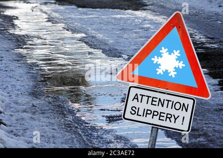 Eine eisige Straße im Winter mit einem Schild Achtung rutschig! Stockfoto