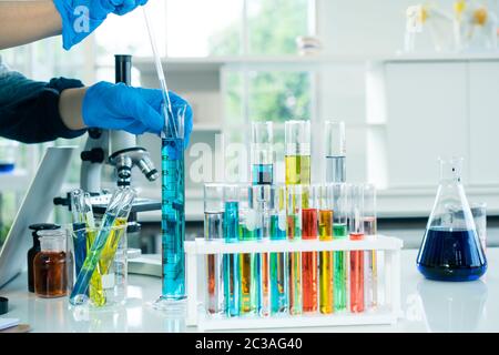 Wissenschaftler arbeiten im Labor auf dem Tisch befindet sich ein Rohr mit verschiedenen farbigen Wasserflaschen. Stockfoto