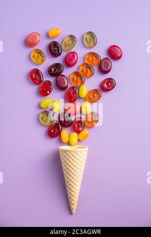 Süße bunte Bonbons in Eis auf Violett Hintergrund. Flache Ansicht. Stockfoto