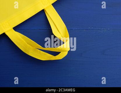 Wiederverwendbarer gelber Viscose-Beutel auf blauem Holzhintergrund, Kunststoff-Abfallreduzierungskonzept Stockfoto