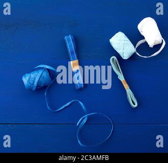 Verschiedene Farbbänder für Geschenkverpackungen auf blauem Holzhintergrund, Draufsicht Stockfoto