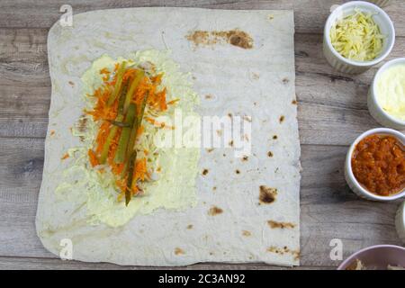 Vorbereitung für die Herstellung von Chicken Shawarma mit Zutaten, Huhn, Adjika, Gurken eingelegter, Shawarma-Sauce, koreanische Karotten, Kohl und Stockfoto