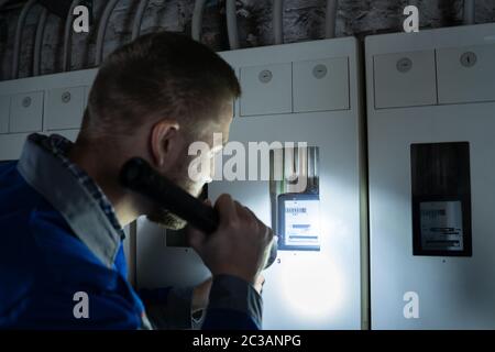 Nahaufnahme von einem Elektriker überprüfen Ein Sicherungskasten mit einer Taschenlampe Stockfoto