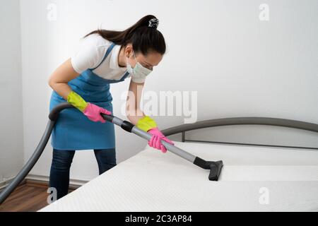 Matratzenreinigung Professional Service von weiblichen Reiniger mit Staubsauger Stockfoto