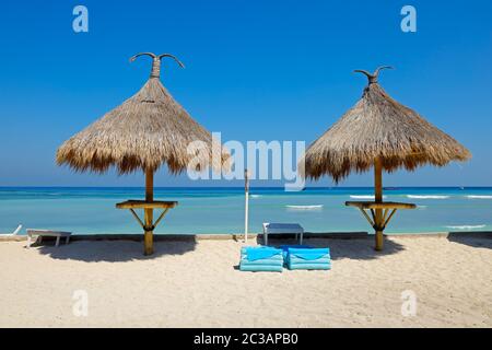 Reetgedeckte Farbtöne auf einer malerischen tropischen Insel Strand, Bali, Indonesien Stockfoto