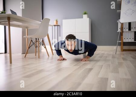 Junge Unternehmer tun Push Up im Büro Stockfoto