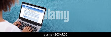 In der Nähe von Frau Füllung Umfrage Formular auf digitalen Tablet vor blauem Hintergrund Stockfoto