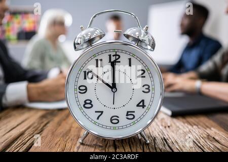 Nahaufnahme der Wecker Vor Geschäftsleute Arbeiten im Büro Stockfoto