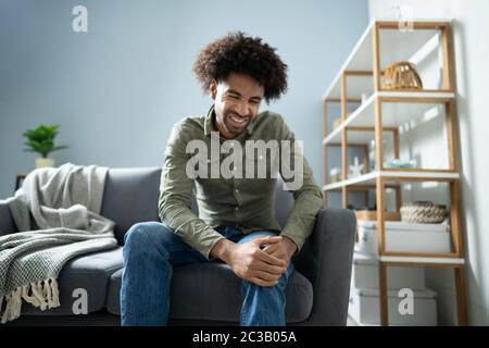 Menschen leiden unter Knieschmerzen Sitzen auf einem Sofa Stockfoto