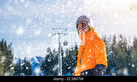 Gerne männliche Skifahrer das Tragen von Helm und Schutzbrille unter das Kabel an Schweiz Stehende Stockfoto