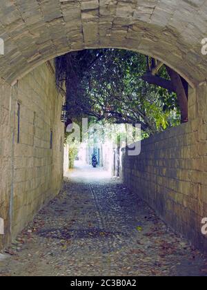 Typische ruhige gepflasterte Straße in rhodos Stadt mit einem Steinbogen und alten Gebäuden Stockfoto