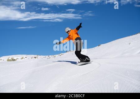 Glückliche junge männliche Snow Boarder genießen Reiten Snow Board auf Schiene gegen Schneebedeckte Berge Stockfoto