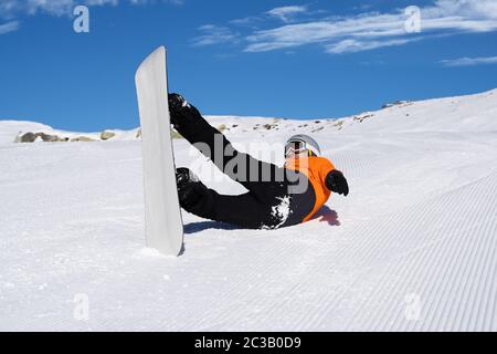 Ein Mann in Orange Jacke Fallen beim Reiten Snow Board auf Schnee, Anschluss Stockfoto