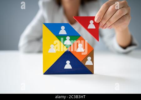 Die Geschäftsfrau Hand Gebäude Tangram Square Block mit menschlichen Figuren Stockfoto